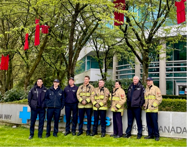 Firefighters in front of PBC building after helping to hang Red Dresses